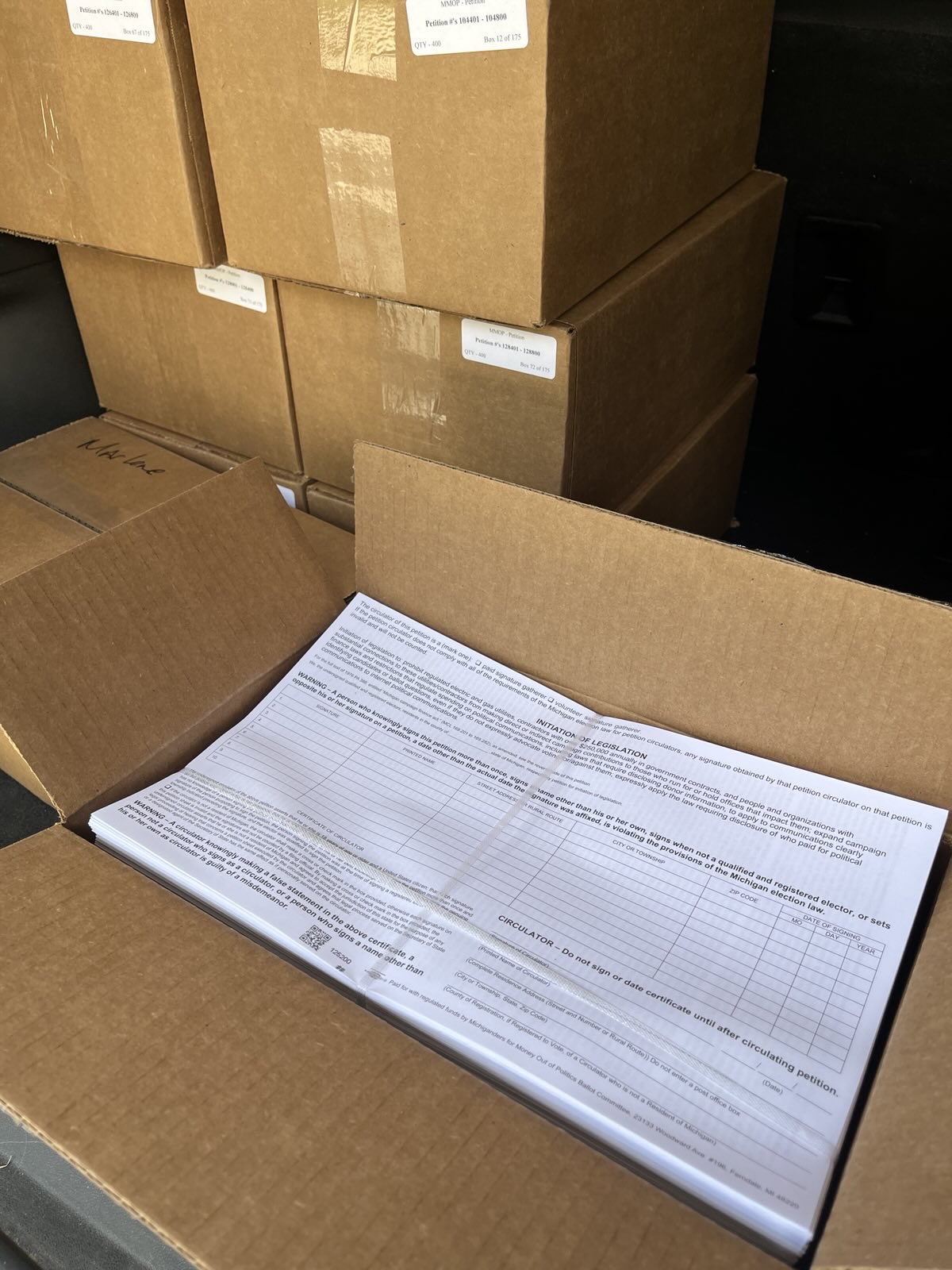 Open cardboard boxes with stacks of paper forms inside.